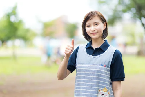 親指を立てるエプロン姿の保育士