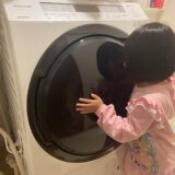 ドラム式洗濯乾燥機を抱える子供